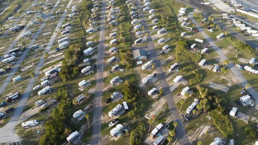 Aerial view of a wooded campground filled with RVs and travel trailers