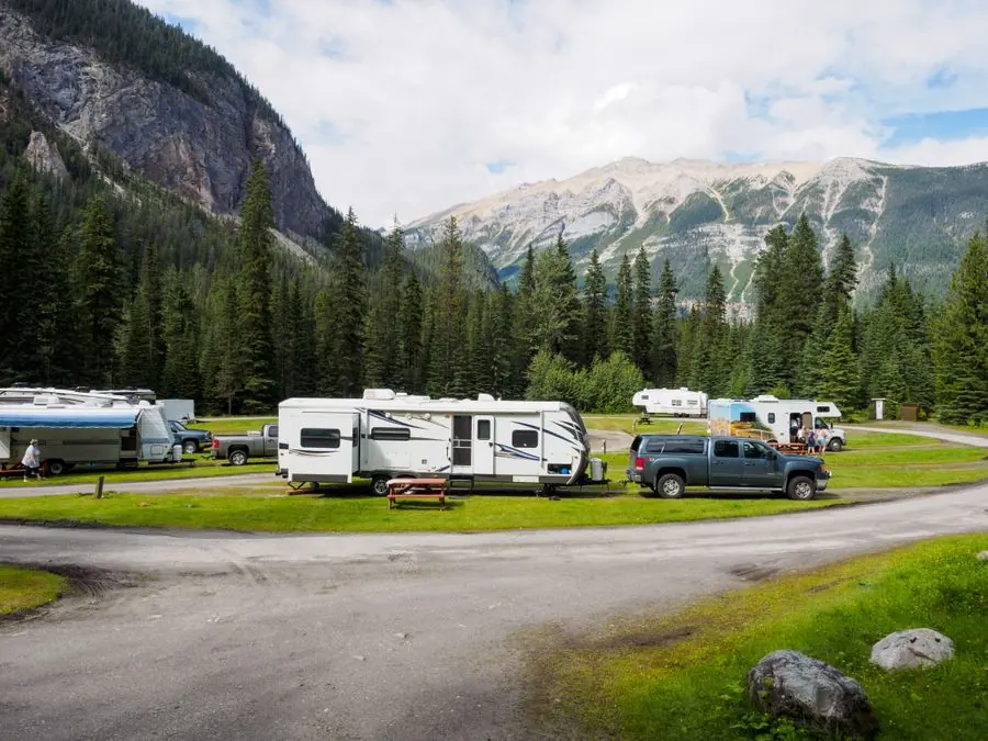 Travel trailer and pickup truck at a campsite with mountains in the distance